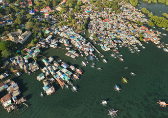 Aerial drone view of the floating fishing village in Coron, Palawan, Philippines. Traditional stilt houses, colorful rooftops, and Filipino outrigger boats line the coastal waters © akturer