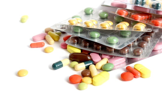 On a white background there are many brightly colored medicines, tablets and capsules.