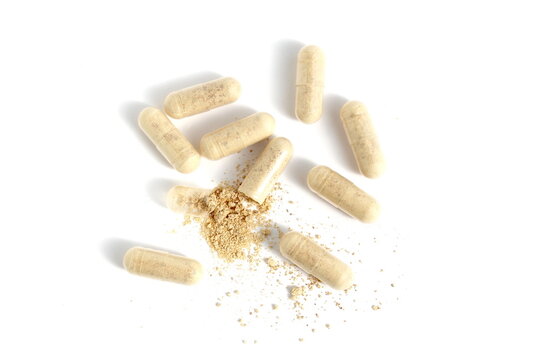 There are many transparent capsules with beige medicine on a white background.