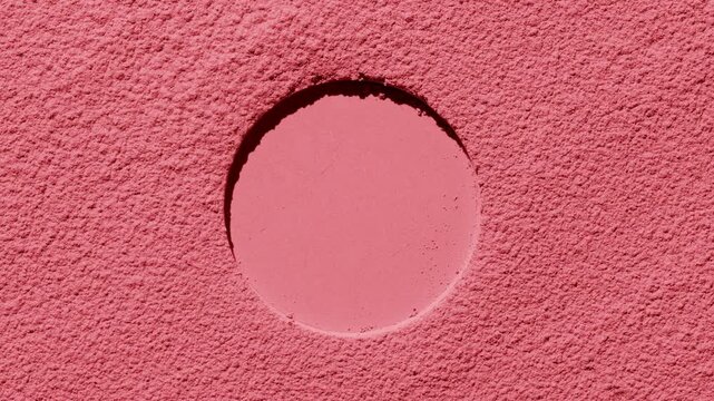 Top perspective shot of red refined sifted powder surface with a round pressed mark highlighted by rotating directional light that forms changing shadows | Idea for blush promotion