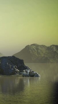 Calm water reflecting hills under morning light. There are rocks on one side and distant mountains in the background creating a natural landscape.