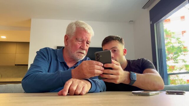 A young man teaches an older man how to use a smartphone, fostering intergenerational connection and digital literacy in a modern world.