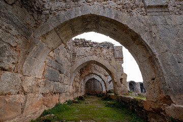 Fototapeta premium Ruins of a historic Seljuk caravanserai standing within the Mediterranean countryside of Antalya, Türkiye, reflecting the architectural heritage of ancient Anatolian trade routes.