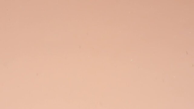 Ultra-close slow-motion shot of two beige pressed powders colliding on a beige surface | Matte powder creative ad concept