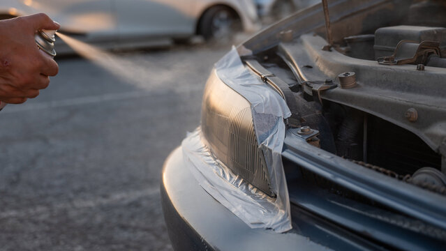A man sprays headlights. The polishing process.