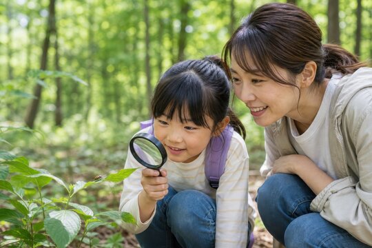 森で虫眼鏡を使い自然観察する母娘