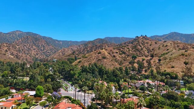 Heading to the Hollywood Hills on sunny day. Drone flight over the beautiful residential area of Los Angeles, California, USA.