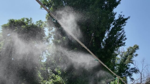 Water mist cooling system spraying outdoor in public park on a hot summer day