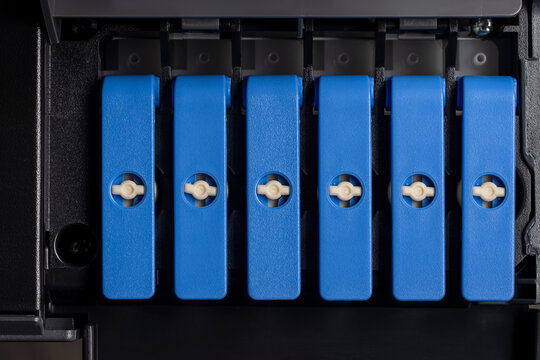 Closeup of blue plastic levers locking mechanism inside an inkjet printer or ciss system. Concept for computer hardware repair maintenance office equipment and digital printing technology