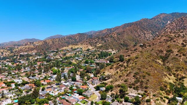 Flying over the residential area at the foot of the mountains with scarce vegetation. Verdugo Mountains in Glendale, California, USA.
