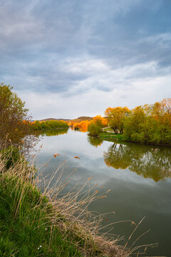 Calm water of river Mures with sunlit hills in the distance, central Transylvania, Romania.