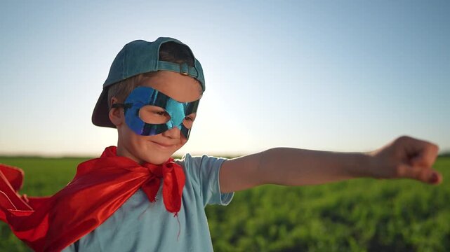 Boy wearing mask with cape smiling. Child pretending superhero outdoor playing fun. Happy boy loves cape. Smiling child enjoys outdoor game. Masked boy pretending superhero child outdoor happy.