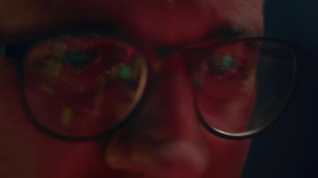 Close up: man crypto trader wearing glasses closely analyzes cryptocurrency or stock market data with candlestick charts and financial graphs, reflecting in lenses, monitoring trends. Eyeglasses