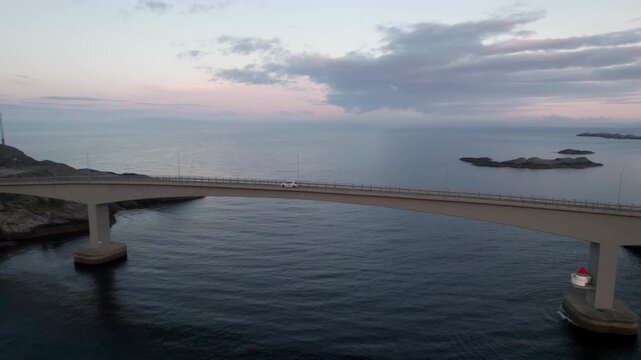 Aerial view of a vehicle driving on the Fredvang bridges at dusk. Scenic Norwegian landscape with sea and islands in the background