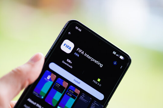 Close-up of a hand holding a smartphone displaying the FIFA Interpreting app on the Google Play Store