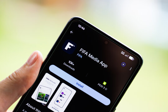 Close-up of a hand holding a smartphone displaying the FIFA Media App on the Google Play Store