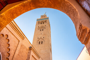 Naklejka na ściany i meble Koutoubia Mosque stands tall in Marrakech, Morocco. The image shows the mosque tower viewed through an archway. Clear blue sky is visible above the building.