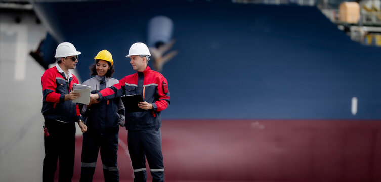 Industrial engineering and port operations concept. Diverse engineers and technicians discussing logistics and maintenance planning at commercial shipping harbor site