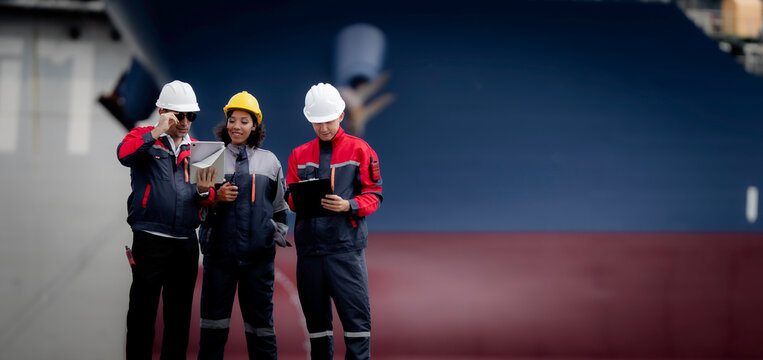 Industrial engineering and port operations concept. Diverse engineers and technicians discussing logistics and maintenance planning at commercial shipping harbor site