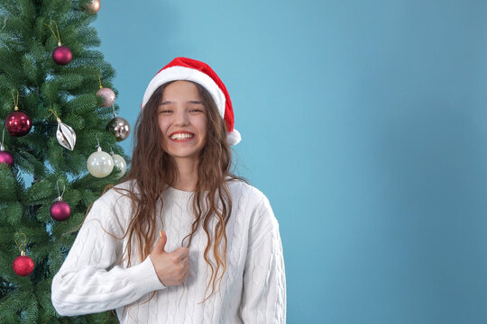 Happy smiling young woman celebrating christmas near decorated pine tree
