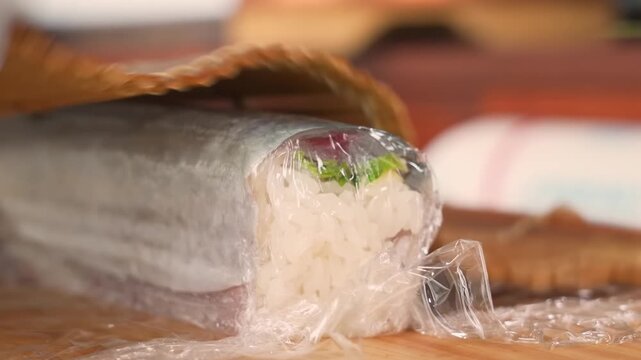 High-angle, close-up shot of a professional chef using a sharp knife to carefully slice through a delicate, layered seafood roulade or terrine. The dish features visible layers of fish, vibrant green 