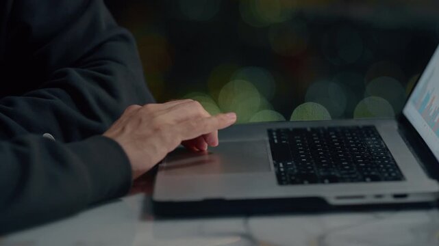 Hand on computer keyboard. Man trader trades on stock exchange on laptop at home at night, lives in a skyscraper, a night city. Male investor analyzes stock market and cryptocurrencies. BTC Ethereum