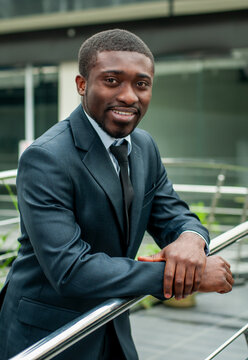 Confident businessman leaning on railing in modern office.
