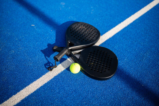 Padel rackets and ball on blue court line