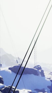 A person stands on a snowy terrain with mountains visible in the background. Structures are scattered in the landscape, showing signs of winter weather.