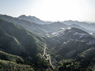 Fototapeta premium Winding road through green mountains and valleys under bright sunlight