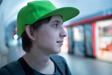  Profile portrait of teenage boy in green cap standing on subway station platform © Ruslan Russland