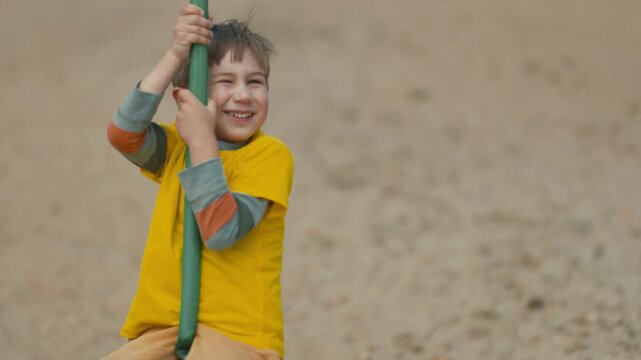 Happy young boy riding a zip line at the playground