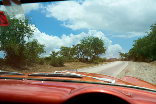 Passing through the cuban countryside from the perspective of an orange vintage vehicle