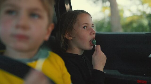 Kids enjoy lollipops while sitting in car during a trip on a sunny day