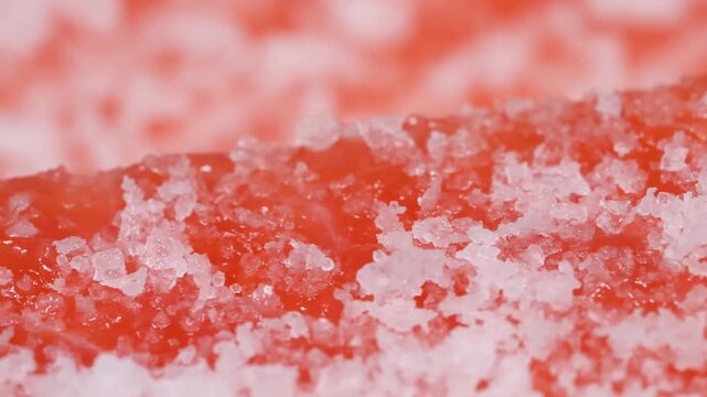 A high-detail macro shot of vibrant red organic texture covered in shimmering white ice or sugar crystals. This abstract footage captures the intricate patterns and glistening surfaces, perfect for fo