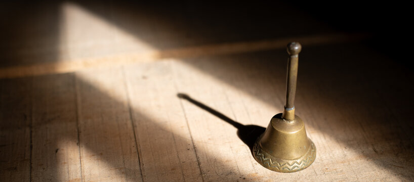 Catholic altar bell with shadow on wooden surface