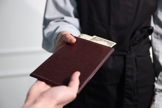 Client giving bill presenter with tips to waiter in restaurant, closeup
