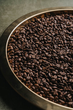 Granos tostados de caf&eacute; sobre charola dorada.