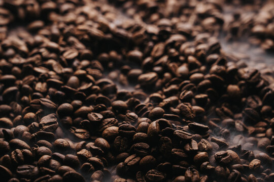 Granos de caf&eacute; reci&eacute;n tostados sobre charola dorada.