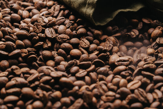 Granos de caf&eacute; reci&eacute;n tostados sobre charola dorada.