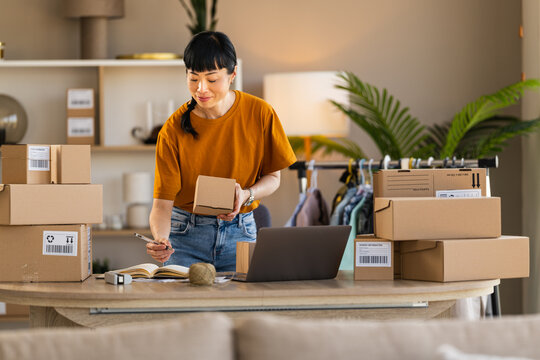 Woman packing online orders at home office for small e-commerce business