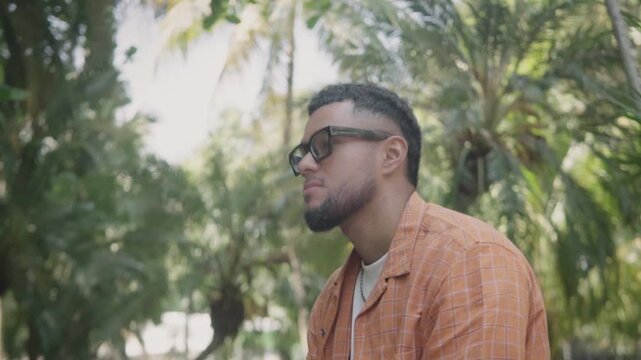 Young hispanic man thinking in a park
