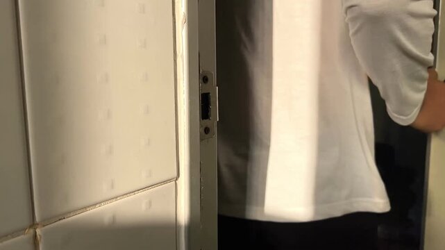Close up man holding door knop and open the toilet door then come out from toilet. Man with white shirt coming out from toilet 