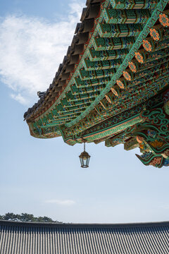 Traditional dancheong patterns on wooden eaves with a hanging decorative glass lantern at a korean building
