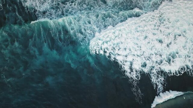 Turquoise ocean waves creating white sea foam, moving and breaking over the water, Bukit Peninsula, Bali. Nature background. Natural power. Aerial view nature background, drone top down shot