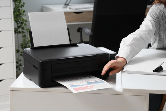 Businesswoman using modern printer in office
