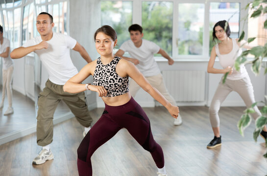 Girl, together with dance youth group, rehearses performance, works out succession of events movements execution of dancing show, modern energetic dances.