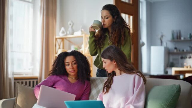 Diverse students studying home browsing laptops together watching screen. 