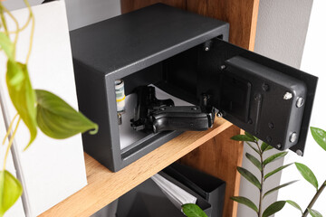 Open safe with pistol, bullets and money on shelf at home, closeup © Pixel-Shot
