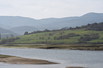 Fototapeta premium Calm Estuary with Green Hills and Distant Mountains